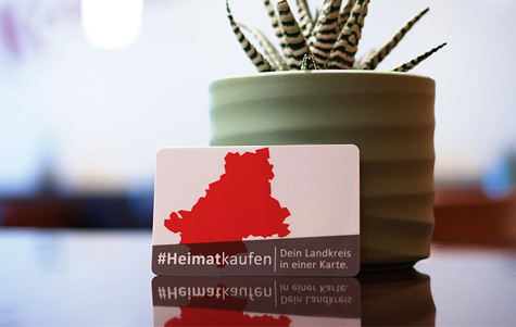 Gutschein auf einem Tisch, angelehnt an einen Zimmerpflanzentopf