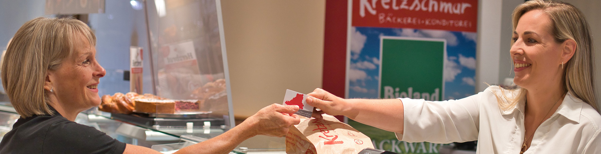 Zwei Damen bei der Übergabe eines Gutscheins.