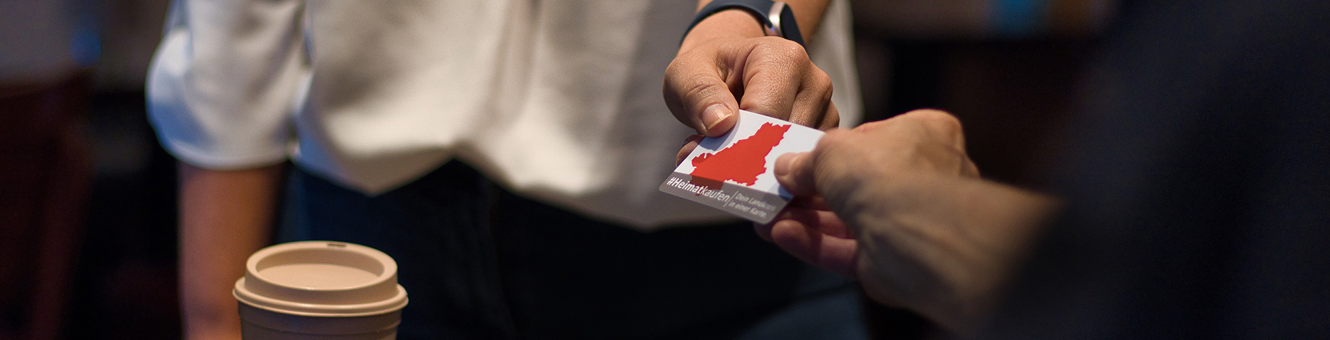 Nahaufnahme zweier Hände, die einen Gutschein übergeben